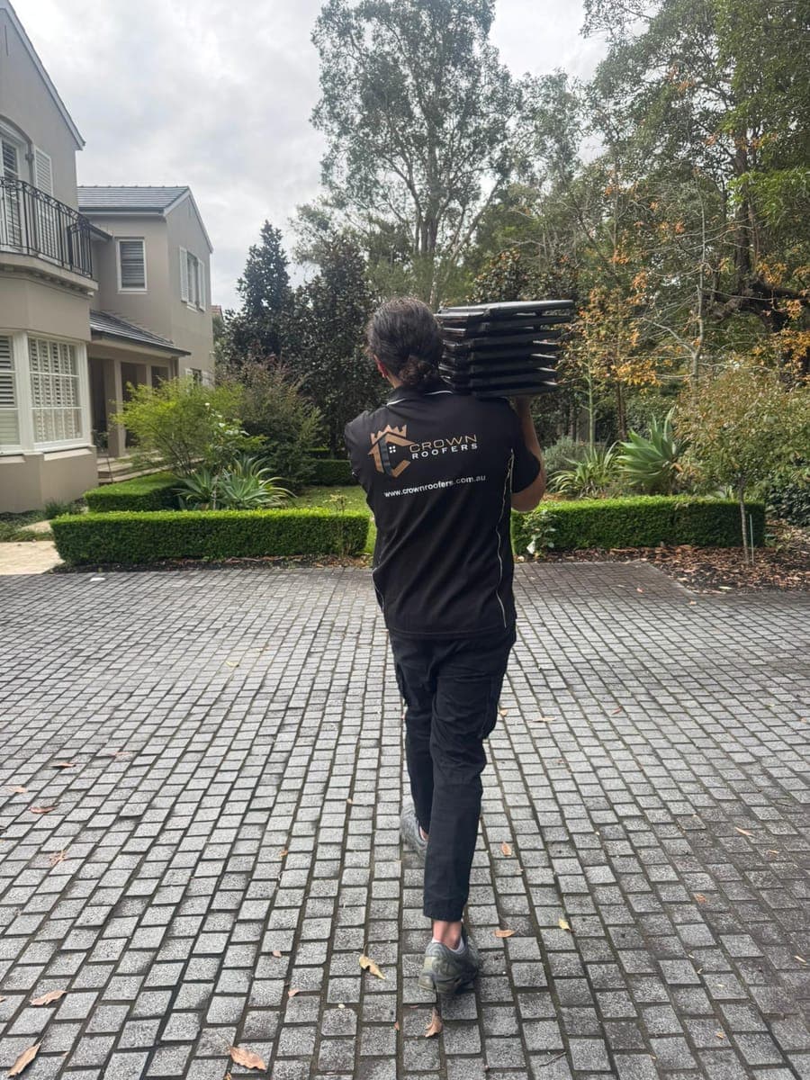 Crown Roofers tradesperson carrying roof tiles on a Sydney job site