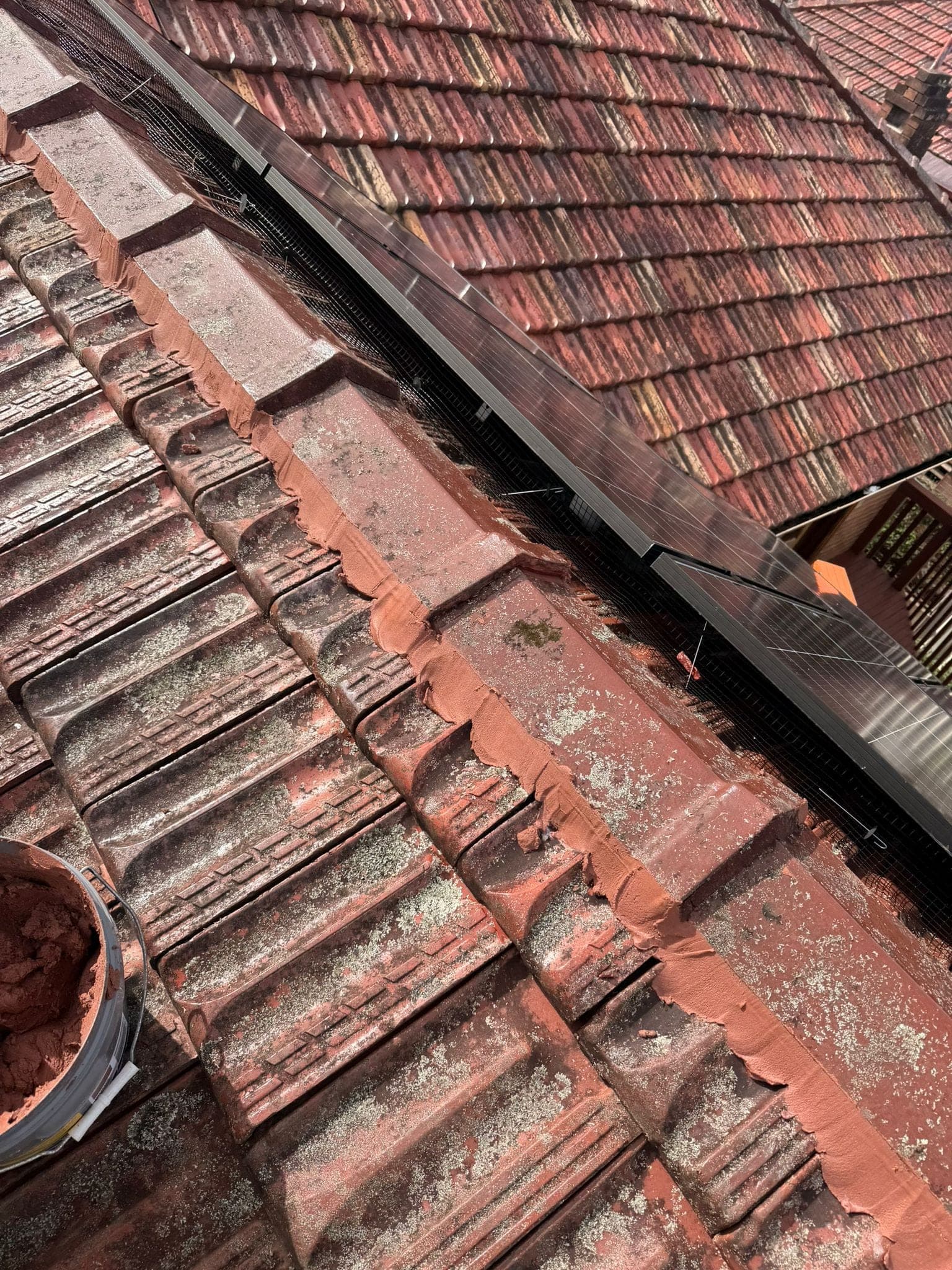 Aged terracotta tile roof with solar panels — Crown Roofers tile restoration project Epping North Shore Sydney — photo 22
