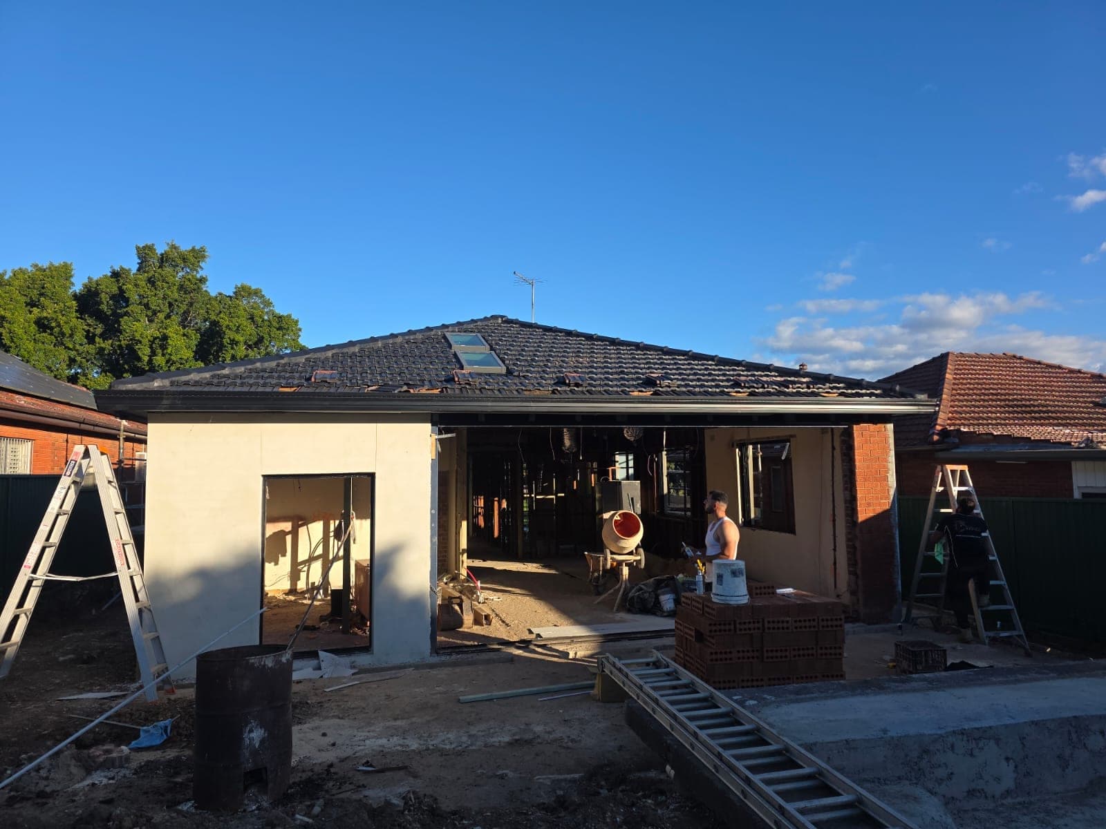 Tile roof restoration and new guttering Crown Roofers Kingsgrove — restored charcoal tile roof and hip lines against a clear sky